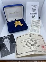 Camrose & Kross gold colour ribbon brooch in blue velvet box with photo of Jackie Kennedy, certificate of authenticity, and information sheet.