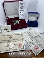 Overall view of the butterfly brooch and green and gold ring with authenticity certificates and branded boxes