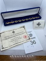 Red jeweled bracelet in a blue velvet Camrose & Kross box with certificate of authenticity and auction card showing 8 inches length.
