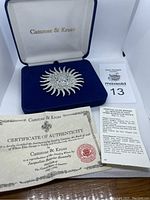 Photo showing the brooch in a blue velvet display box with 'Camrose & Kross' logo on the inside cover and certificate of authenticity included.