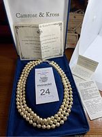 Full view of triple strand faux pearl necklace displayed with certificate of authenticity and original box.