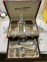 Top view of open cutlery case showing forks, knives, spoons, and serving utensils neatly arranged.