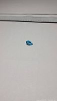 Photo of 2.31ct natural Swiss blue topaz pear cut gemstone on a white background, showing shape and color.