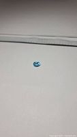 Photo of natural oval cut blue topaz gemstone lying on a white surface.