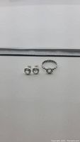Photo showing pair of round clear crystal quartz stud earrings and oval clear crystal quartz ring in sterling silver, front view.