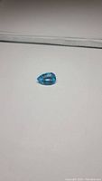 Photo of pear-shaped natural Swiss blue topaz on white background showing color and size