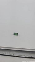 Image showing the rectangular cut electric green tourmaline gemstone on a plain white background.
