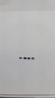 Four small oval cut multicolored sapphires laid out in a row on white background, colors ranging among blue, green, and yellow hues.