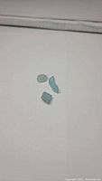 Three small natural aquamarine crystals placed on a white background showing shape and color