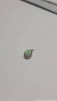 Oval cabochon cut Ethiopian opal pendant set in 925 sterling silver, showing play of color and oval shape.
