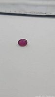 Close-up photo of a deep red oval cut ruby, showing its deep color and polished surface.
