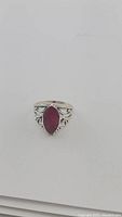 Full view of the natural deep red marquis cut ruby ring with detailed scrollwork sterling silver band