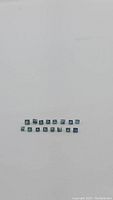 Top view of 20 loose natural princess cut blue sapphire gemstones arranged in two rows showing their square cut and blue colors.
