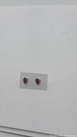 Pair of pear cut natural ruby earrings on display card, showing size and color