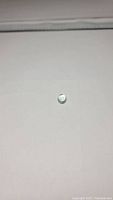 Top view of a small oval cabochon aquamarine gemstone showing smooth polished dome and light blue tint.