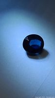 Oval deep blue faceted sapphire on white background