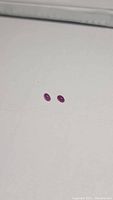 Pair of oval pink-red cabochon rubies on white background