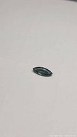 Close-up image showing the marquis cut green sapphire with vibrant color and facets visible.