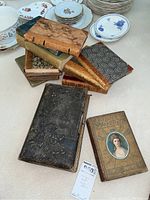 Stack of antique books showing varied cover designs including marbled and leather-bound hardcovers
