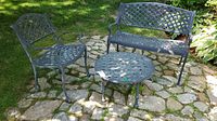 Image showing entire patio set with bench, chair, and table arranged on stone patio outdoors.