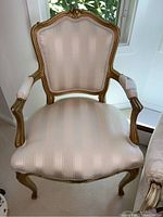 Front view of the French style armchair showing cream damask upholstery, gold enameled carved wood frame, and padded armrests.