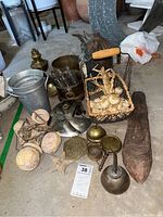 Overview photo of copper, brass, and vintage items including pots, oil can, bell, basket with dried roots, coaster, and carved wooden piece