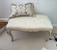 Full view of upholstered seat with decorative pillow on top showing fabric pattern, legs, and overall condition.
