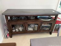 Front view of the rustic metal and wood sideboard cabinet showing three glass doors and items inside.