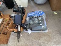 Six composite post solar lights with gray finish and built-in LEDs arranged in a plastic tray, alongside four different solar light styles and a plastic planter with coir liner.