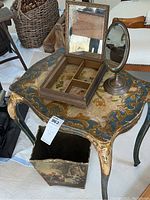 Wooden side table with gold and blue painted top holding a jewelry box with interior mirror and an oval standing mirror.