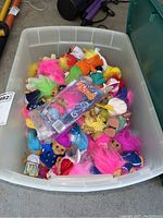 Clear plastic bin filled with numerous loose Troll dolls with neon hair and varied outfits