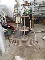 Front view of the three-tier wrought iron corner shelf showing the tiered shelves and curved feet.