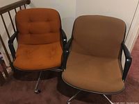 Two vintage office chairs side by side showing different fabric colors and armrest styles.