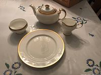 Four-piece Aynsley tea service set, includes teapot with lid, creamer, open sugar bowl, and serving platter on floral tablecloth.