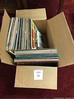 Top down view into a cardboard box showing a large number of vinyl records packed vertically inside