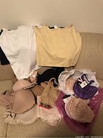 Overview of beige and pink bras, white and beige camisoles laid on couch