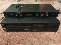 ADC DD-4AX delay processor stacked on top of Samsung VHS VT-210TB player on carpet floor.