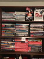 Three shelves on a bookcase filled with stacked MacUser and Macworld magazines from the 1990s and 2000s, with two magazine covers visible upright on the top shelf.