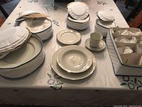 Set displayed on table showing various pieces including stacked plates and cups along with their padded storage holders.