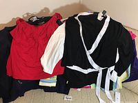 Photo of red top and black and white wrap-style jacket with hood over assorted clothing items