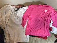 White and pink new women's tops with tags, laid out on surface