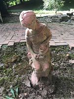 Outdoor sculpture of a sitting woman shown close-up from the front, displaying detailed features and weathering on the surface.