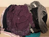 Photo showing six women's clothing items including a purple patterned blouse, striped jacket, black shirt with necklace, and additional jackets.