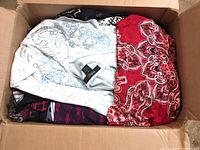 Opened box showing stacked women's tops in various colors and patterns, highlighting the mix and condition.