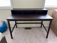 Front view of dark wooden desk featuring built-in raised shelf with three compartments