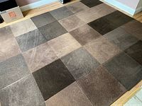 Carpet tiles arranged on floor showing patchwork pattern of various shades of brown