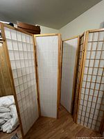 Two identical Japanese paper folding privacy screens standing in a room, partially open and showing wooden lattice frames and white paper inserts.