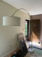 Full view of modern arc floor lamp showing white drum lampshade, adjustable curved arm, and large marble base.