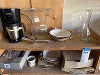 Top shelf showing coffee maker, glass vases, plates and mugs.