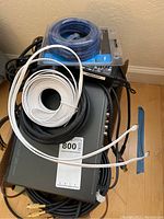 Photo of stacked electronics and various coiled cables including Philips DVD player, power adapters, and Ethernet cables.